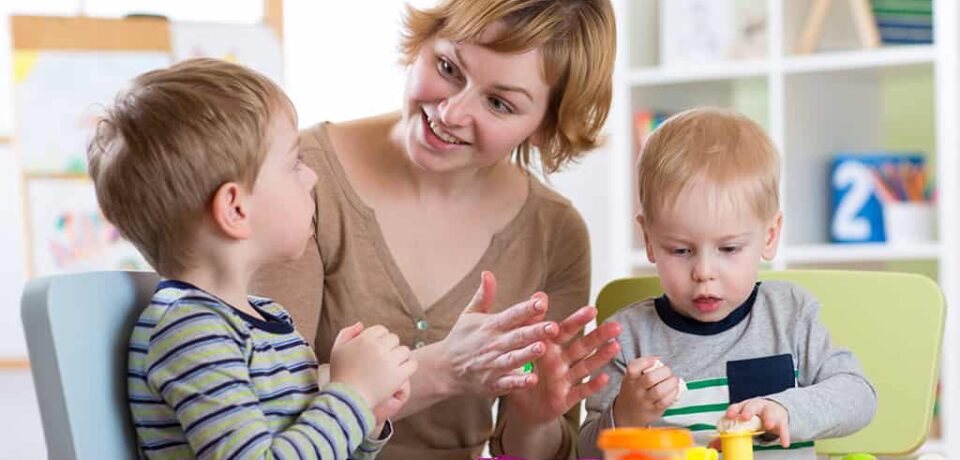 Woman and kids boys with play clay toys at day care center